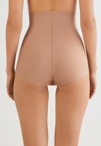 Högmidjade, sömlösa shapewear i en slät, stretchig tyg i en nude-färg, med en subtil lyster och mjuk finish.