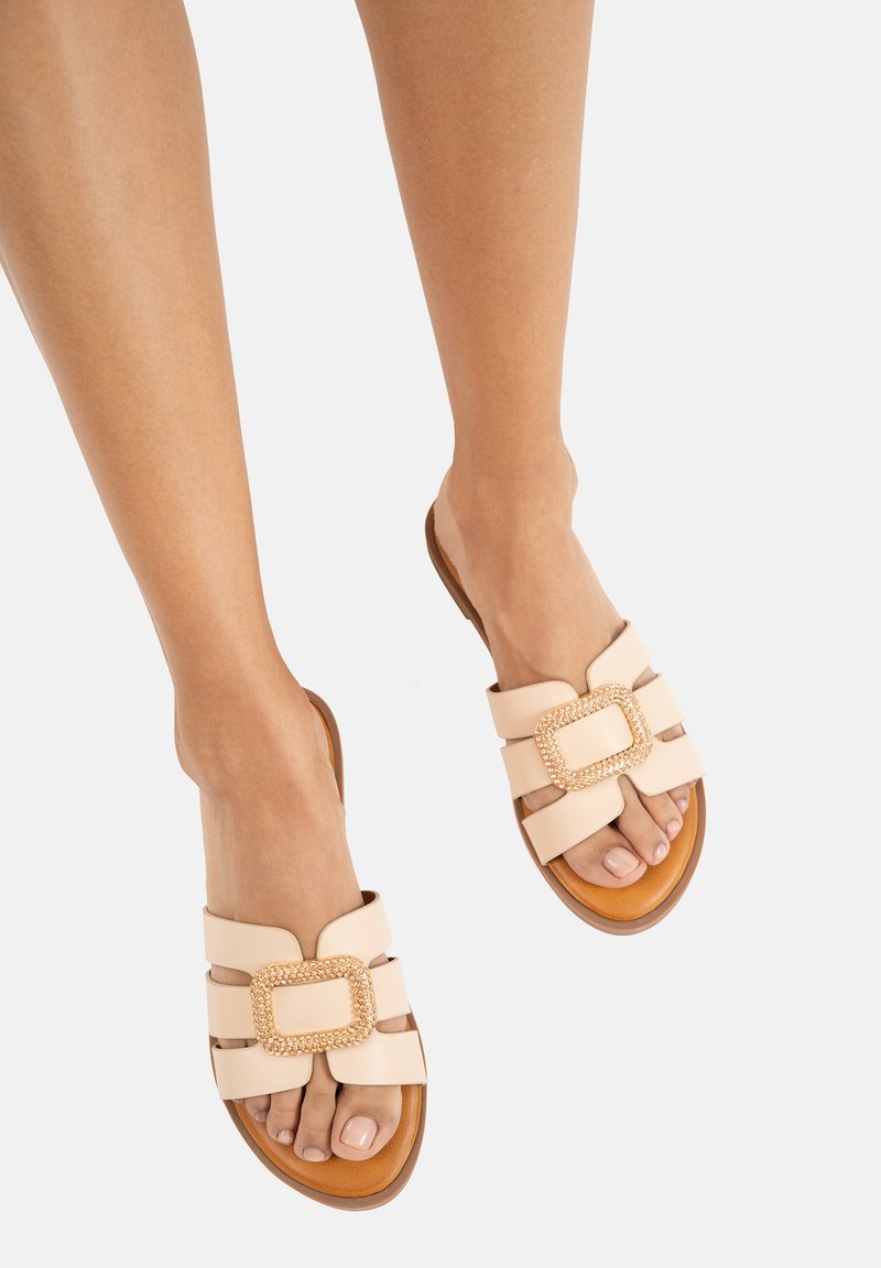 Sandali nude senza cinghie con fibbia dorata, dotati di tre fasce larghe e una suola piatta marrone. Materiale in pelle liscia e design aperto sulla punta.