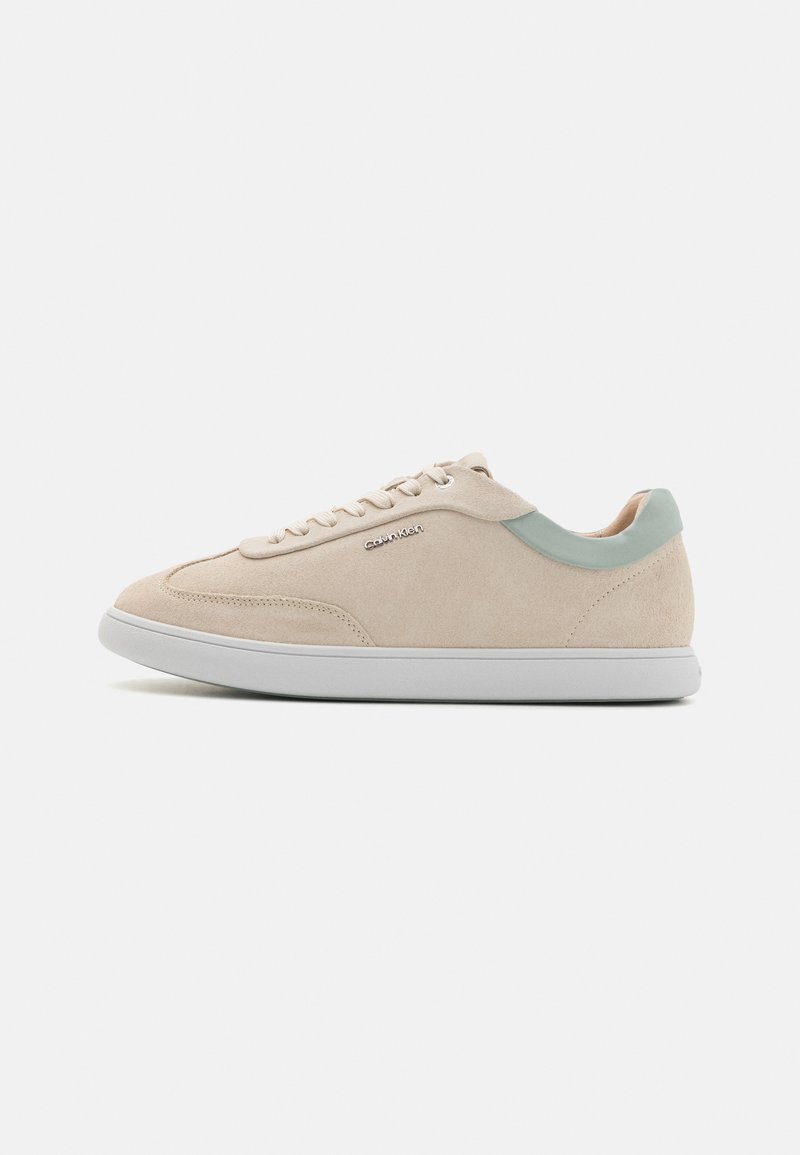 Sneaker in suede beige con un accento verde chiaro sul tallone, suola in gomma bianca e chiusura con lacci, caratterizzata da dettagli di cucitura sottile.