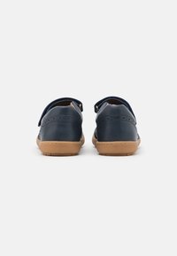 Granatowe skórzane buty z teksturowanym wykończeniem, z brązową gumową podeszwą i regulowanymi paskami z tyłu dla pewnego dopasowania.