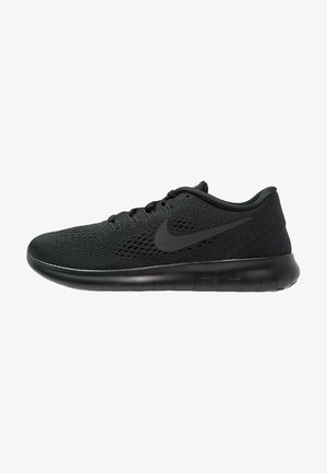Scarpa atletica nera con una parte superiore in mesh traspirante, suola piatta e un prominente logo Swoosh di Nike. Progettata per comfort e supporto.