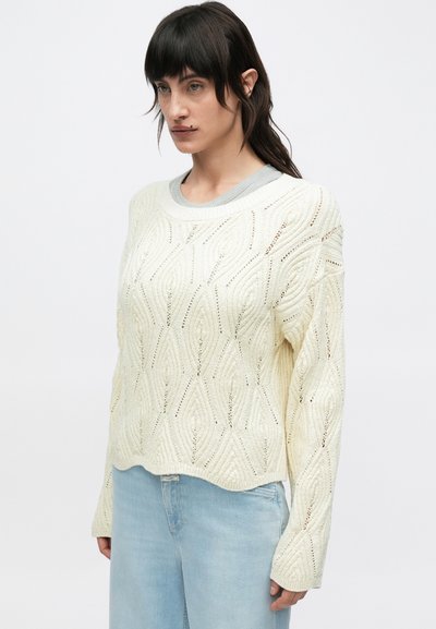 Πλεκτό πουλόβερ σε κρεμ απόχρωση με υφασμένο μοτίβο διαμαντιού και γκρι ριμπ λαιμόκοψη. Μακριά μανίκια και εφαρμογή cropped.