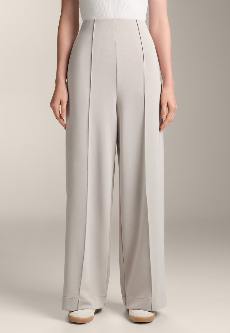 Ljusgrå högmidjade byxor med vida ben, försedda med framfickor och en slät yta. Materialet verkar mjukt och faller välsorterat.