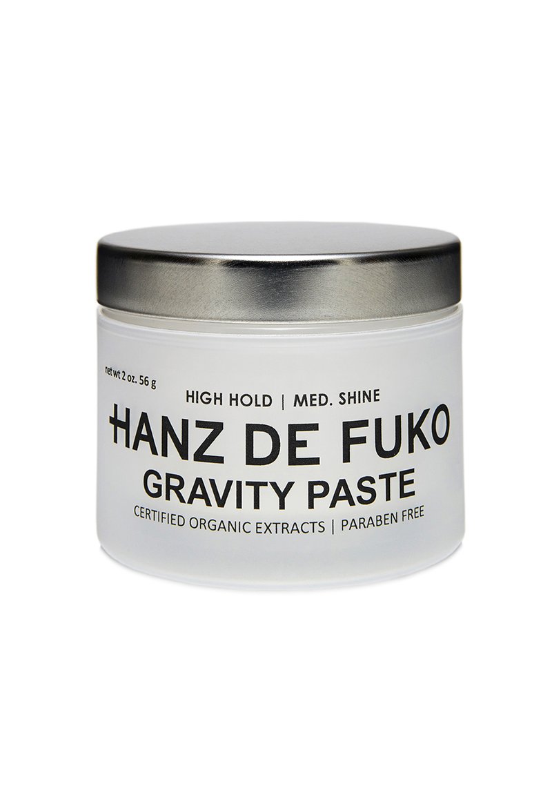 Frostad glasburk med ett lock av silvermetall. Svart text på framsidan står "Hanz de Fuko Gravity Paste," som indikerar hög hållfasthet och medelhög glans.