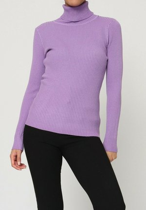 Pull à col roulé côtelé de couleur lilas clair, avec des manches longues et une coupe ajustée, associé à un pantalon noir pour le contraste.