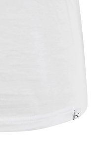 Weißes Baumwoll-T-Shirt mit abgerundetem Saum, weicher Textur und einem kleinen schwarzen Logo-Tag am unteren linken Rand. Minimalistisches Design.