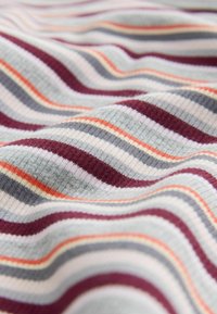 Tissu rayé multicolore présentant des lignes ondulées en gris, bordeaux, orange et crème. Motif texturé en côtes sur l'ensemble.