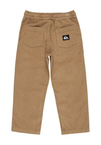 Pantalons en velours côtelé beige avec une taille élastique, jambes droites, deux poches arrière et une étiquette logo sur la poche droite. Tissu texturé.