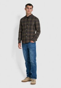 Groen en bruin geruite blouse met knopen en kraag, gecombineerd met blauwe jeans en beige sneakers. Slim fit, met een subtiele logo-detail.