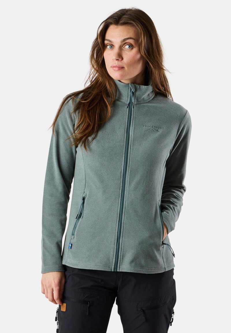 Fleece jacket in muted green, featuring a high collar, front zipper, and two zippered side pockets. Soft texture, minimal branding.
