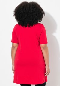 Vestido túnica corto rojo de manga corta, hecho de una tela suave, con un corte holgado y que llega a la mitad del muslo, sin patrones ni acentos visibles.