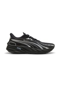 Scarpa da corsa nera realizzata in materiale GORE-TEX, con una tomaia testurizzata, suola curvata e dettagli riflettenti argentati.