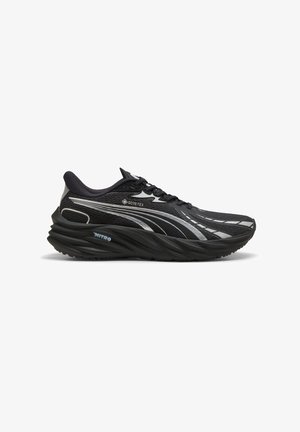 Schwarzer Laufschuh aus GORE-TEX-Material mit einer strukturierten Oberseite, gekrümmter Sohle und reflektierenden silbernen Akzenten.