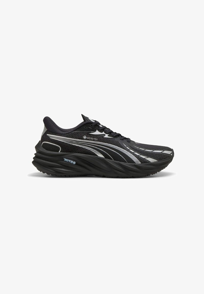 Scarpa da corsa nera realizzata in materiale GORE-TEX, con una tomaia testurizzata, suola curvata e dettagli riflettenti argentati.
