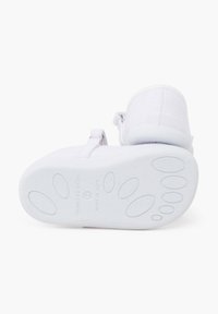 Scarpe bianche con una tomaia in tessuto morbido e una suola testurizzata. Le scarpe presentano una chiusura con strap in velcro e un design minimalista.