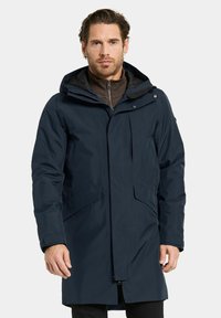 Mörk marinblå vattentät parka med huva, framzippering och två stora sidofickor. Har en mjuk innerfoder och justerbara ärmslut.