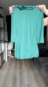 Türkise Langarm-Tunika mit lockerer Passform, die am unteren Rand ein plissiertes Design und einen glatten, glänzenden Stoff aufweist.