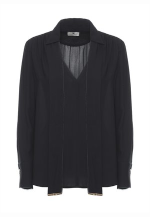Blusa nera a maniche lunghe con scollo a V profondo, lacci larghi che pendono dal colletto e polsini abbottonati con dettagli metallici.