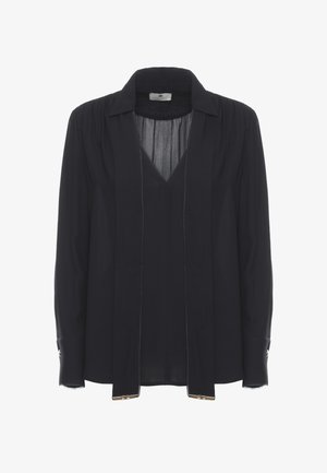 Blouse noire à manches longues avec un décolleté en V profond, des liens lâches suspendus au col et des poignets boutonnés avec des accents métalliques.