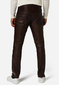 Bruine leren broek met een geribbelde tailleband en twee achterzakken. De stof heeft een gladde textuur, met horizontale stiksels op de bovenbenen.