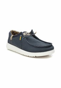 Zapato slip-on de malla en color marino con suela blanca, con detalles en beige y cordones coloridos, tejido texturizado y forro interior a cuadros.