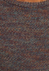 Strickpulloverstoff in einer reichen Mischung aus dunklem Lila, Bronze und türkisfarbenen Fäden; hat eine strukturierte Oberfläche und einen gerippten Halsausschnitt.