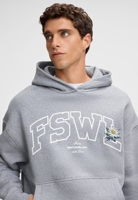 Felpa con cappuccio grigia caratterizzata da una grande stampa bianca "FSWL", con un ricamo floreale sul lato sinistro e una tasca frontale.