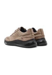 Baskets en daim beige avec semelles en caoutchouc noir, présentant un talon rembourré et des détails de couture discrets sur la section supérieure.