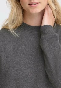 Grå hettegenser med ribbet rund hals og lange ermer. Stoffet er mykt med en glatt tekstur, egnet for hverdagsbruk.