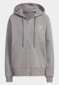 Sudadera con capucha y cremallera en gris claro, hecha de tela suave. Cuenta con dos bolsillos frontales, cordones ajustables y detalle de logo en la parte superior izquierda.