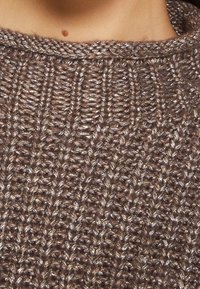 Maglione marrone lavorato a maglia con un motivo testurizzato, caratterizzato da un colletto tondo e una miscela di fibre opache e lucide per un contrasto sottile.