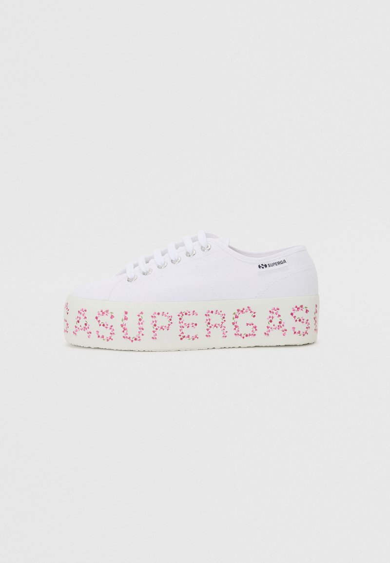 White canvas sneaker with pink floral pattern on the platform and “SUPERGA” text. Features round laces and metallic eyelets. Flat sole.