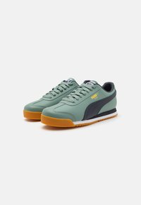 Roheline nahast sneakerid halli triibuga, kummist põhjaga ja valge vaheosaga. Omavad paelu ja kollast logo küljel.