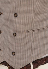 Brązowa kamizelka w wzór houndstooth, z zapięciem na guziki i kieszonką po bokach, z teksturowanej tkaniny oraz kontrastowym wykończeniem.