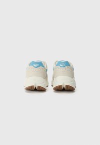 Footwear with a light-colored upper made of fabric and suede, blue accents, and a rubber sole featuring a textured, multi-directional tread.