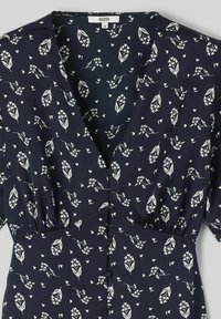 Robe bleu marine avec un motif floral blanc, manches ballons courtes, décolleté en V et boutons sur le devant. Tissu léger avec une texture douce.