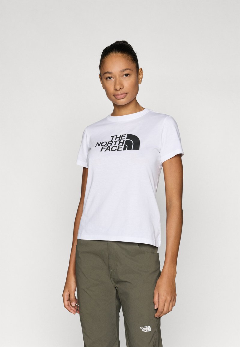 Λευκό βαμβακερό μπλουζάκι με μαύρο λογότυπο σε σχέδιο κειμένου, στρογγυλή λαιμόκοψη και κοντά μανίκια, σε συνδυασμό με παντελόνι ελιάς πράσινου χρώματος.