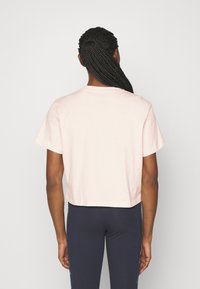 T-shirt rose à manches courtes recadré, en coton doux. Présente un col rond et une coupe décontractée, associé à des leggings foncés.