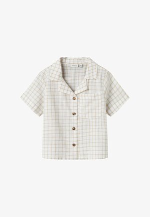 Rövid ujjú, gombos ing fehér és bézs kockás mintával, gallérral és melletti zsebbel, fa gombokkal és laza szabással.