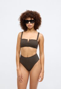 Conjunto de biquíni preto com um padrão geométrico em dourado. O top tem tiras largas e um design de decote em V; a parte de baixo de cintura alta oferece um ajuste suave.