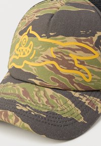 Καπέλο παραλλαγής με ραμμένο κίτρινο σχέδιο καρτούν ψαριού. Το ύφασμα έχει υφή με αποχρώσεις του πράσινου, καφέ και μαύρου.