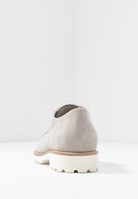 Scarpa in suede grigia con forma arrotondata, suola bianca texturizzata e un midsole naturale simile al sughero. Design minimalista con una superficie liscia.