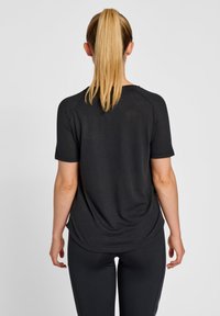 Sort kortærmet træningsskjorte med en afslappet pasform og rund kant, parret med sorte leggings. Glat stof, ingen synlige logoer eller mønstre.