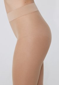 Beige průhledné punčochy s širším elastickým pasem, s hladkou texturou a těsným střihem, zdůrazňující přirozený vzhled nohou.