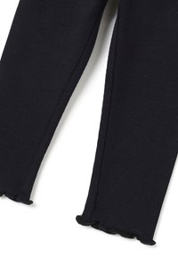 Zwarte geribbelde leggings met een gestructureerde afwerking en een gerimpelde zoom. De stof lijkt zacht en rekbaar, wat zorgt voor een aansluitende pasvorm.