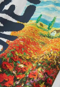 Primer plano de una impresión de tela colorida que muestra un paisaje otoñal vibrante con casas, árboles y campos en tonos rojos, naranjas, verdes y azules.