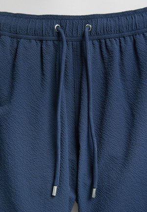 Námořnické modré šortky z texturované tkaniny, s elastickým pasem a šňůrkou s kovovými konci.