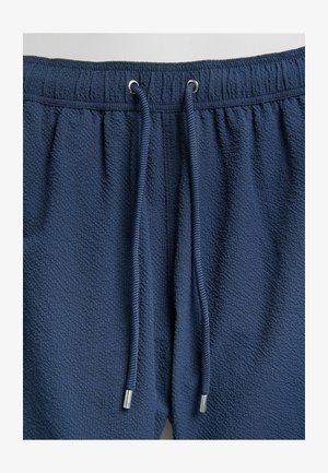 Marineblå shorts i struktureret stof med elastisk talje og snor med metalspidser.