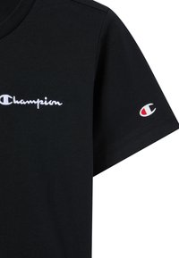 Zwarte katoen t-shirt met een witte geborduurde 'Champion' logo op de borst en een klein logo patch op de mouw. Klassieke ronde hals.