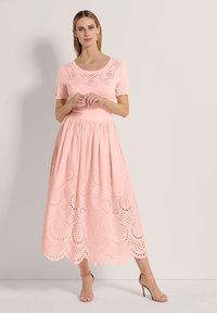 Rosa Baumwollkleid mit einem engen Oberteil mit Lochmuster-Ausschnitten und einem fließenden Rock mit gewelltem Saum und komplizierten Ausschnitt-Designs.